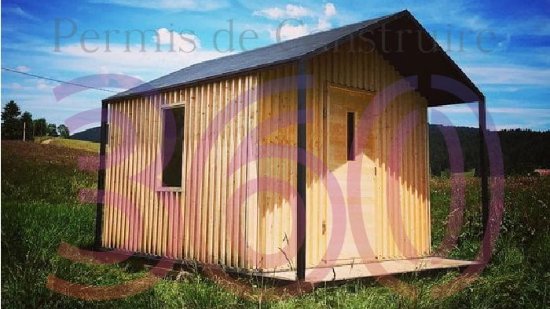 Petite cabane en bois dans un champ, construite avec un permis de construire pour une structure légère.