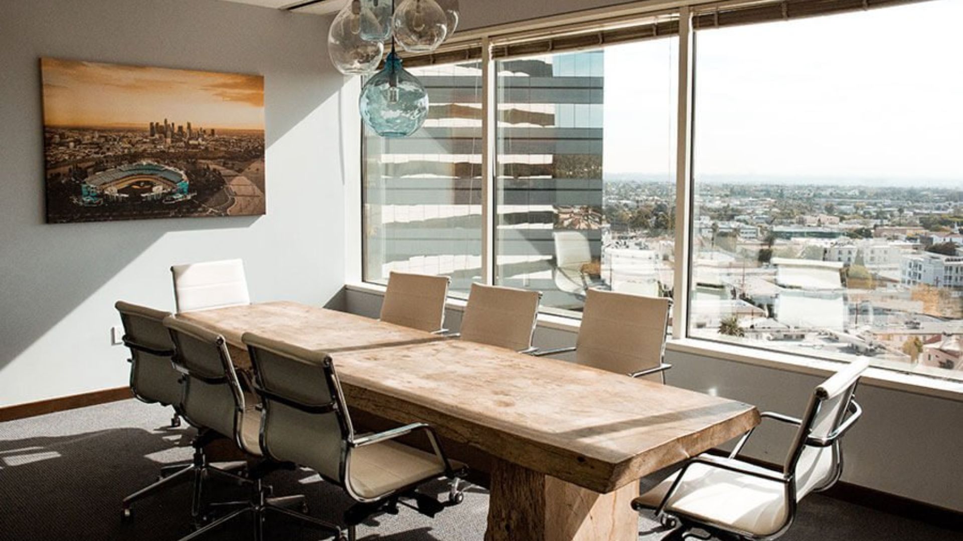 Salle de réunion moderne avec vue panoramique sur la ville, décorée avec une table en bois massif et des chaises ergonomiques.